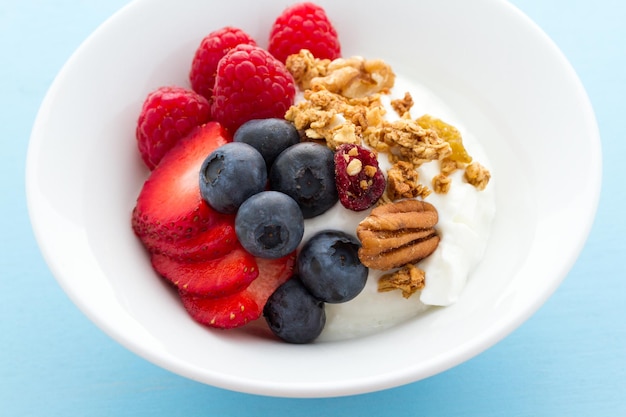 Parfait con frutas frescas y granola en un tazón blanco.