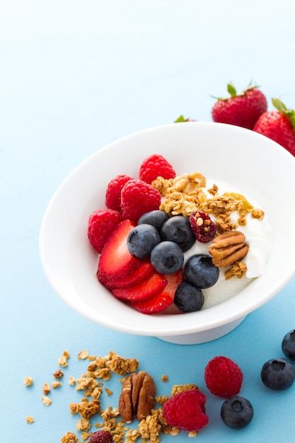 Parfait con frutas frescas y granola en un tazón blanco.