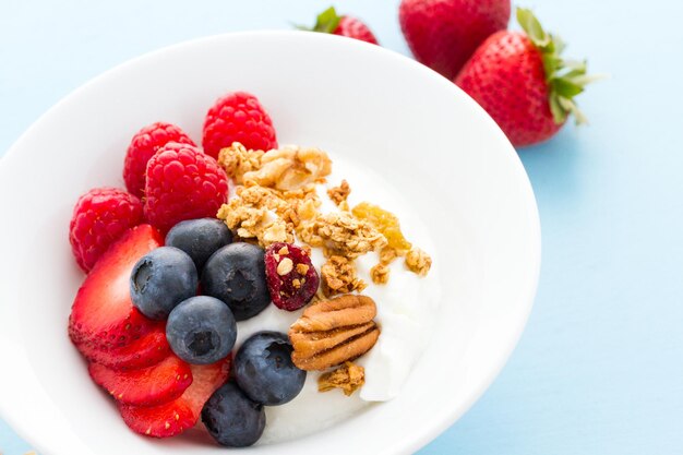 Parfait con frutas frescas y granola en un tazón blanco.