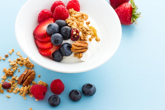 Parfait mit frischen Früchten und Müsli in weißer Schüssel.