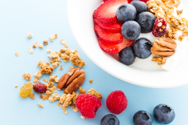 Parfait mit frischen Früchten und Müsli in weißer Schüssel.