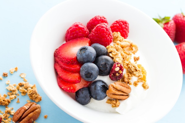 Parfait mit frischen Früchten und Müsli in weißer Schüssel.