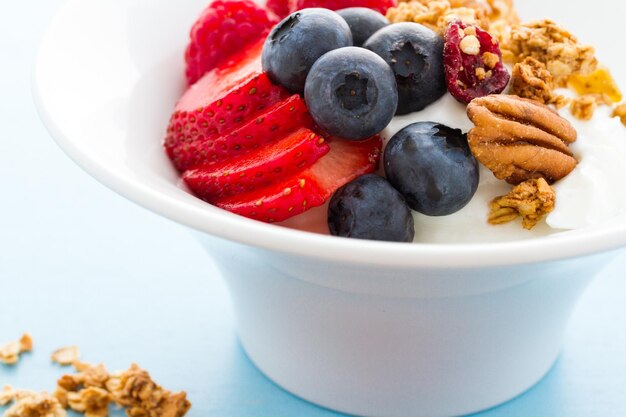 Parfait mit frischen Früchten und Müsli in weißer Schüssel.