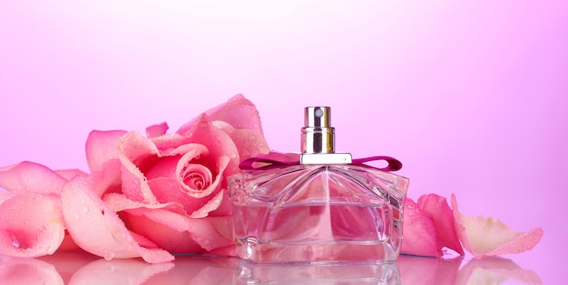 Parfümflasche und rosa Rose auf rosa