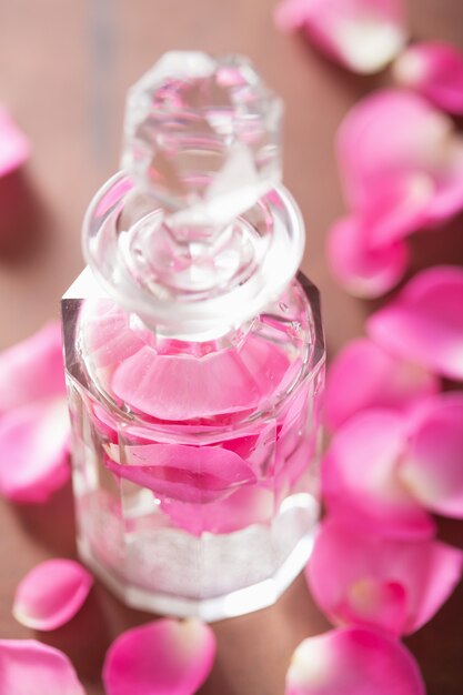 Parfümflasche und rosa Rosenblüten. Spa-Aromatherapie