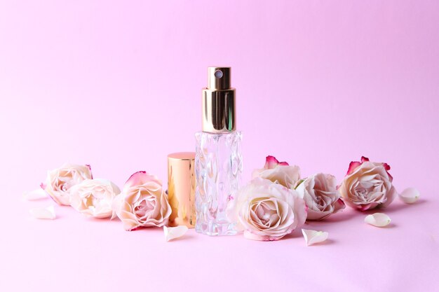 Parfümflasche und Rosenblüten auf hellem Hintergrund hautnah