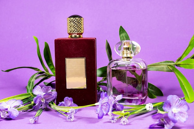 Parfümflaschen mit Blumen, die auf lila Hintergrund isoliert sind