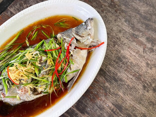 El pargo se cocina al vapor con salsa de soja y se sirve en un plato blanco Menú de pescado estilo comida tailandesa