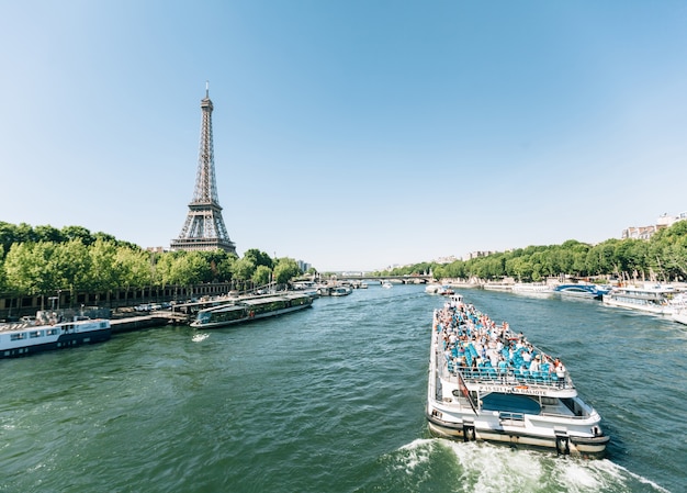 Paris, França - 19 de junho de 2017: Vista da Torre Eiffel, vista do rio pela manhã com um céu azul ao fundo e um barco se movendo ao longo do rio Sena