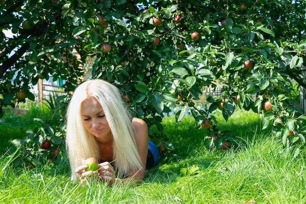 Parks und Erholungsgebiete Das Mädchen ruht unter einem Baum auf dem Rasen und hält einen Apfel