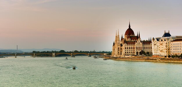 Foto parlamento de budapeste ao pôr-do-sol perto do rio danúbio