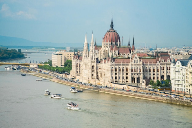 Parlamento húngaro de pie en el banco de Pest del Danubio y barcos de viaje navegando por el río en Budapest Hungría