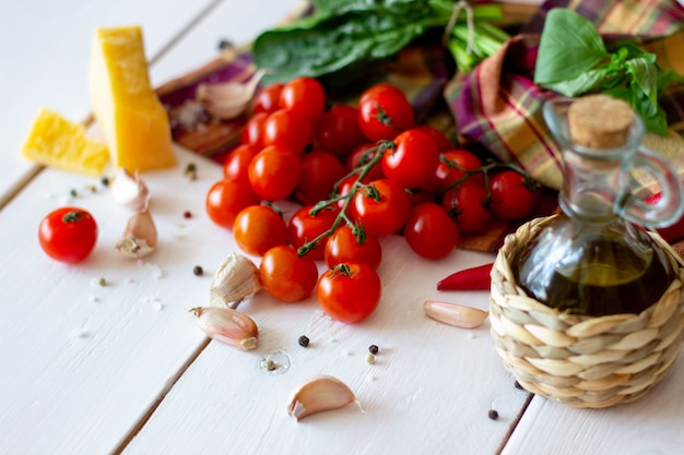 Parmesano, tomates, aceite de oliva y otros ingredientes para aderezo de ensaladas. Fondo blanco.