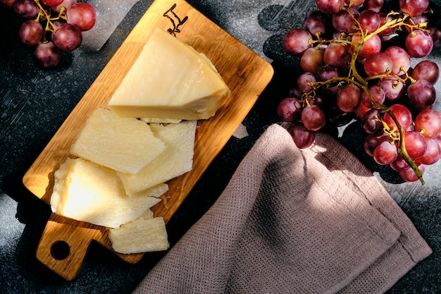 Parmigiano-Käse auf hölzernem Schnittbrett mit Traubenbeeren