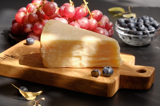 Parmigiano-Käse auf hölzernem Schnittbrett mit Traubenbeeren