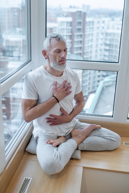 Parnayama. Um iogue maduro fazendo pranayama e parecendo meditativo