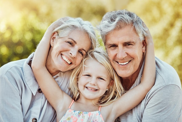 Parque de abuelos y retrato de abrazo infantil con una niña y personas mayores con amor y sonrisa Cuidado de la unión y la naturaleza de una familia que se siente feliz con un niño y un abuelo mayor