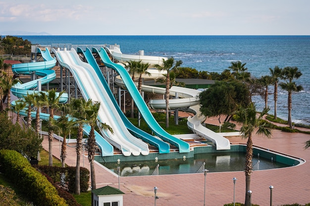 Un parque acuático para discapacitados con toboganes altos junto al mar con una gran piscina sin tratar sin gente en un hotel en una ciudad turística