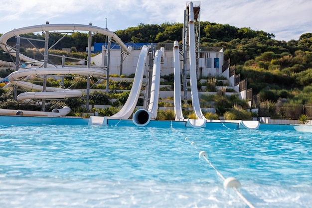 Parque acuático vacío con toboganes blancos altos y tumbonas blancas