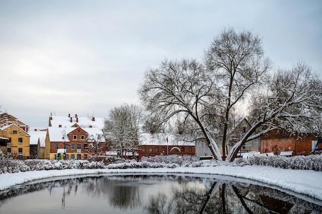 Parque de la ciudad de Kandava con un estanque y reflejos de árboles en el agua en un día de invierno Letonia