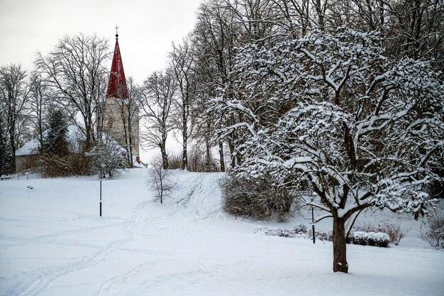 Parque de la ciudad con puente de estanque e iglesia al fondo en un día de invierno nevado Kandava