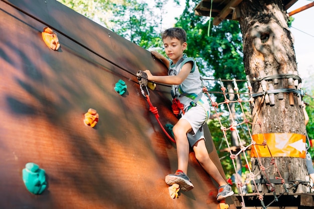 Foto parque da corda. a criança passa o obstáculo no parque de cordas.