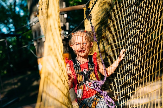 Foto parque da corda. a criança passa o obstáculo no parque de cordas.