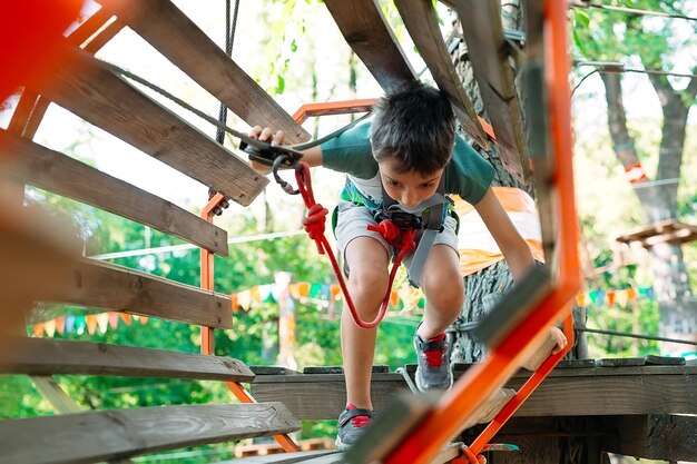 Parque da corda. A criança passa o obstáculo no parque de cordas.