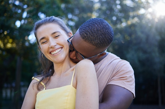 Parque do amor e beijos com um casal inter-racial se unindo ao ar livre em um encontro romântico na natureza Romance de verão e diversidade com um homem e uma mulher namorando ao ar livre em um jardim verde