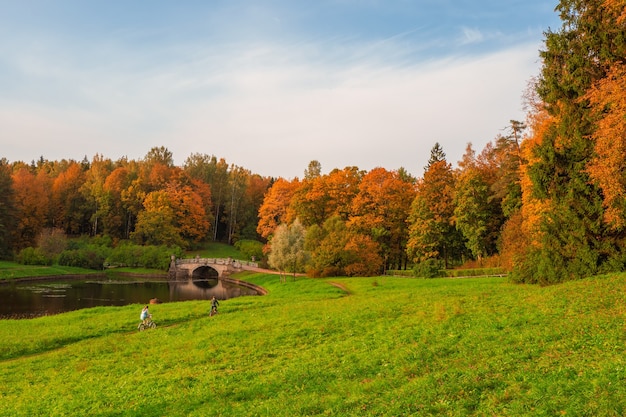 Parque do outono de pavlovsky. alguns ciclistas na trilha. rio slavyanka em pavlovsk, são petersburgo, rússia