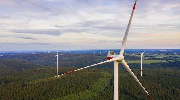 parque eólico na floresta ao pôr do sol - produção de energia com energia limpa e renovável - tiro aéreo