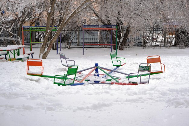 Parque infantil con columpios, en invierno, cubierto de nieve.