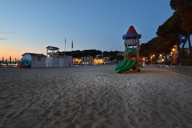 Un parque infantil en la playa al atardecer.