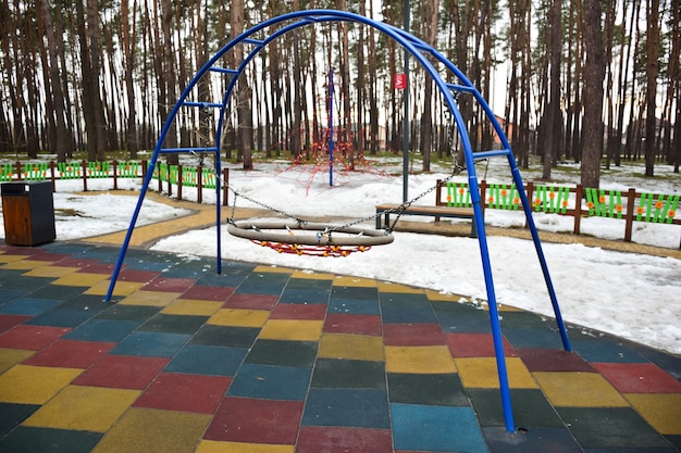 Foto en un parque de invierno en el bosque, un columpio decorativo vacío sin niños