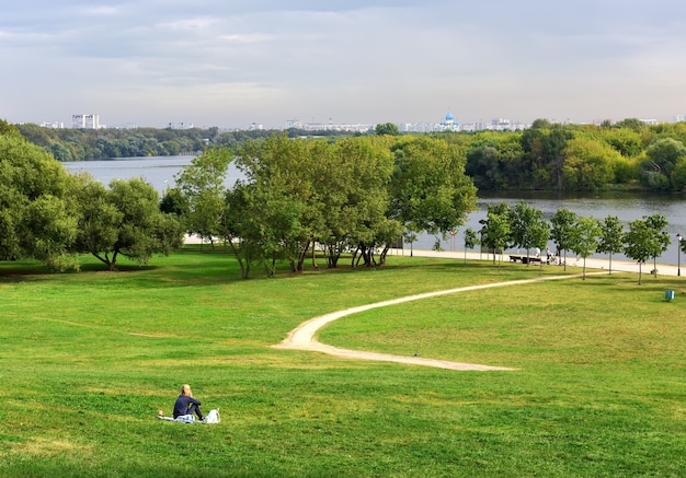 Parque Kolomenskoe en verano La niña en el prado en una pendiente verde que desciende hasta el río