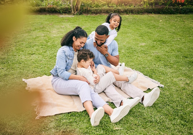 Parque lúdico y familia con amor feliz y tiempo de calidad para relajarse unión y amor juntos padres madre en el césped y padre con niños niños y diversión al aire libre alegre y felicidad