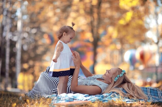 parque de otoño madre e hija tiradas en el suelo jugando