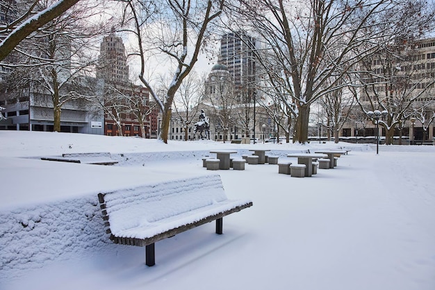 Parque urbano nevado con bancos y estatua de Fort Wayne