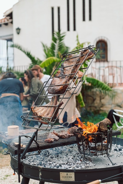 Una parrilla con carne y una mujer al fondo.