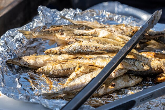 Una parrilla con pescado y un par de pinzas.