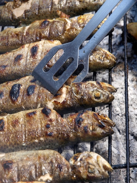 Una parrilla con pescado y un par de pinzas