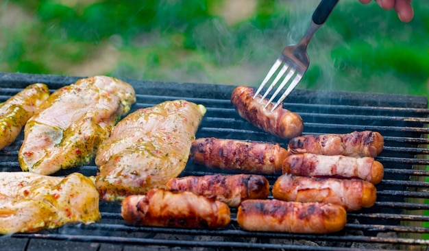 Parrillada variada de carne de pollo y cerdo, salchichas asadas en una parrilla de barbacoa cocinadas para la cena familiar de verano.