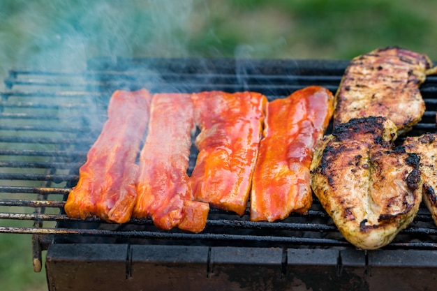 Parrillada variada de carne de pollo y cerdo, salchichas asadas en una parrilla de barbacoa cocinadas para la cena familiar de verano.