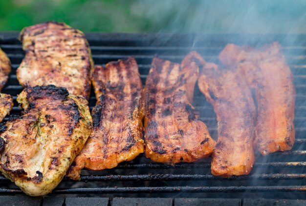 Parrillada variada de carne de pollo y cerdo, salchichas asadas en una parrilla de barbacoa cocinadas para la cena familiar de verano.