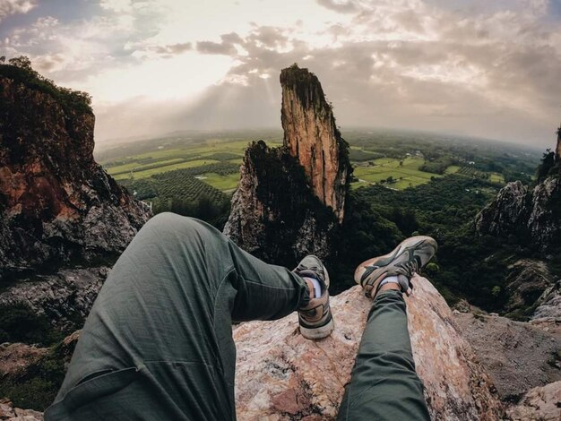 Foto parte baja del hombre en la roca contra el cielo