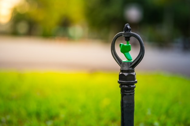 Una parte de la cabeza del rociador de jardín ubicada en el fondo del área verde pública.