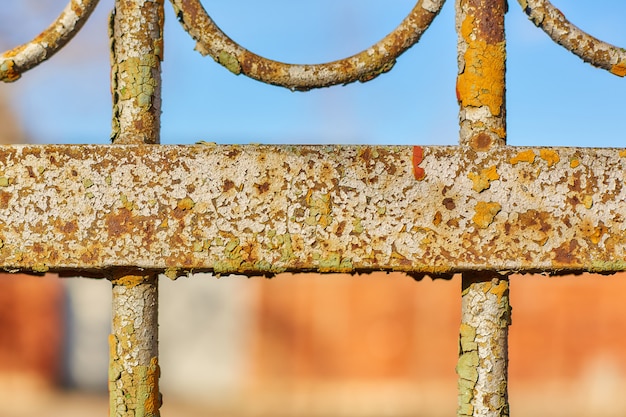 Parte de una cerca vieja, de hierro, oxidada contra un cielo azul