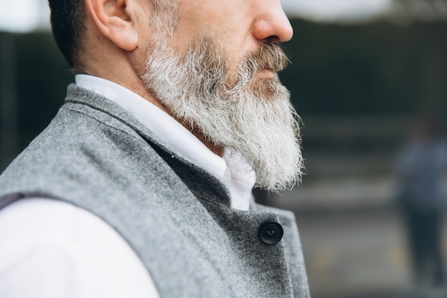 Parte del cuerpo. Un hombre de barba gris y bigote con traje.