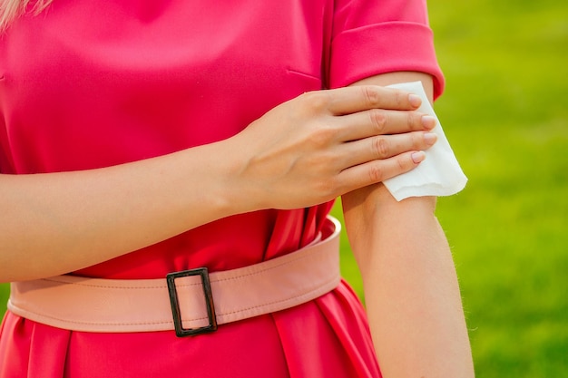 Parte del cuerpo de una mujer joven en un parque rosa chica usando toallitas húmedas el sudor en el brazo