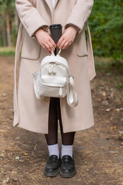 Parte del cuerpo de una niña con una mochila y una copa en las manos